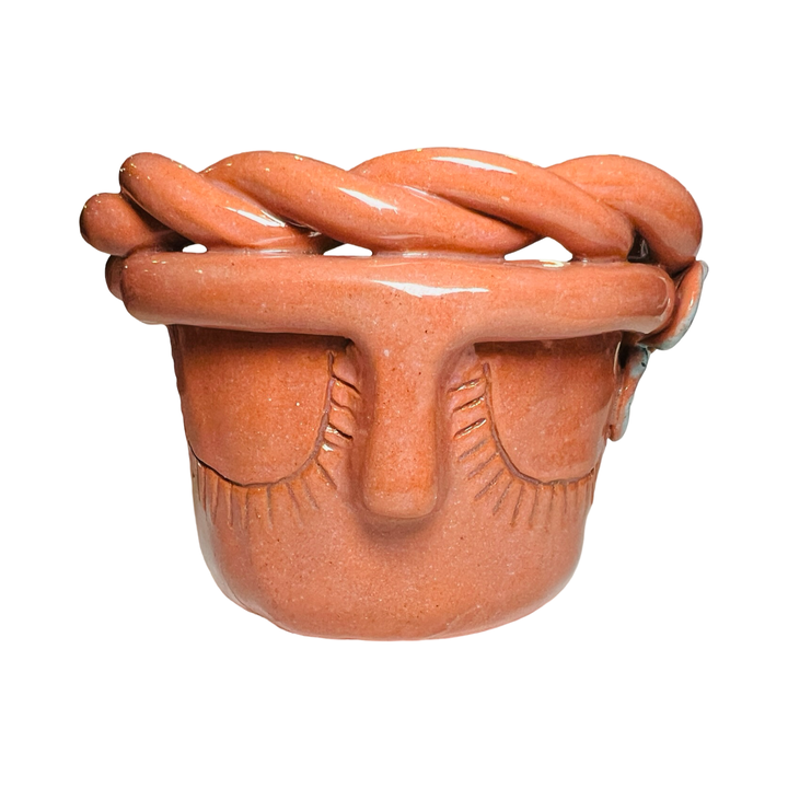 front view of a terracotta espresso cup made of barro (clay) with a glazed finish, featuring a face design and braided detailing around the rim.