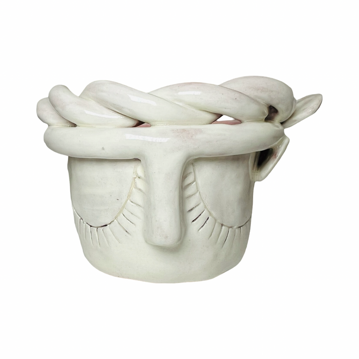 front view of a espresso cup made of barro (clay) with a glazed finish, featuring a face design and braided detailing around the rim.