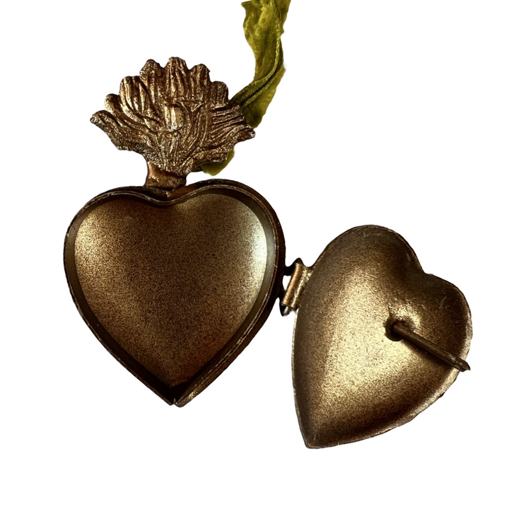 close up view of a brass heart locket featuring an engraved design and green velvet hanging loop