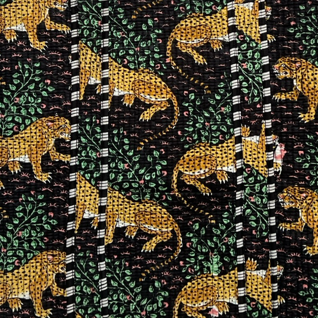 close up view of a tiger print with greenery on a black background.