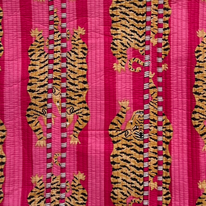 close up view of a orange and black tiger print on a pink and dark pink striped pattern.