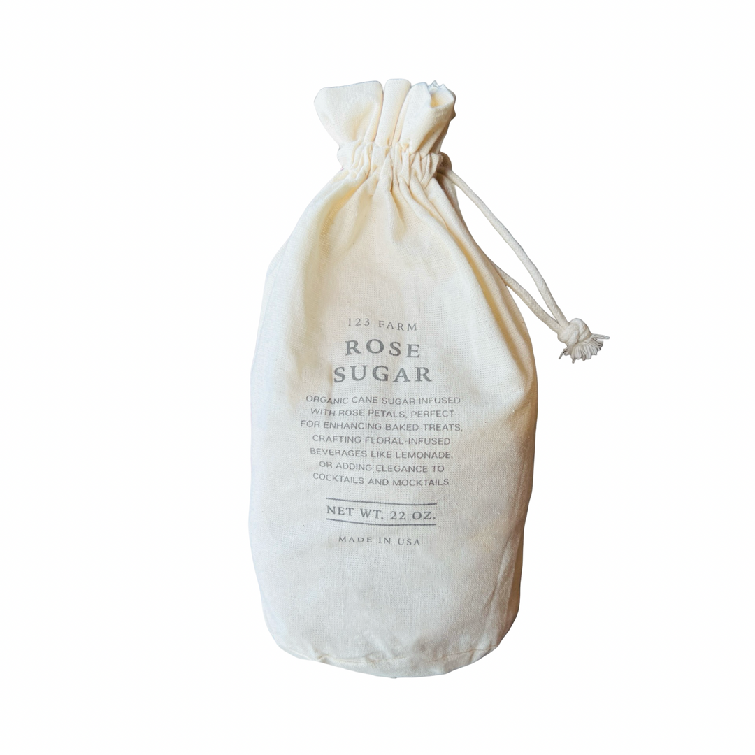 A rustic fabric bag labeled "Rose Sugar" from 123 Farm, featuring organic rose essential oil blended with organic cane sugar.