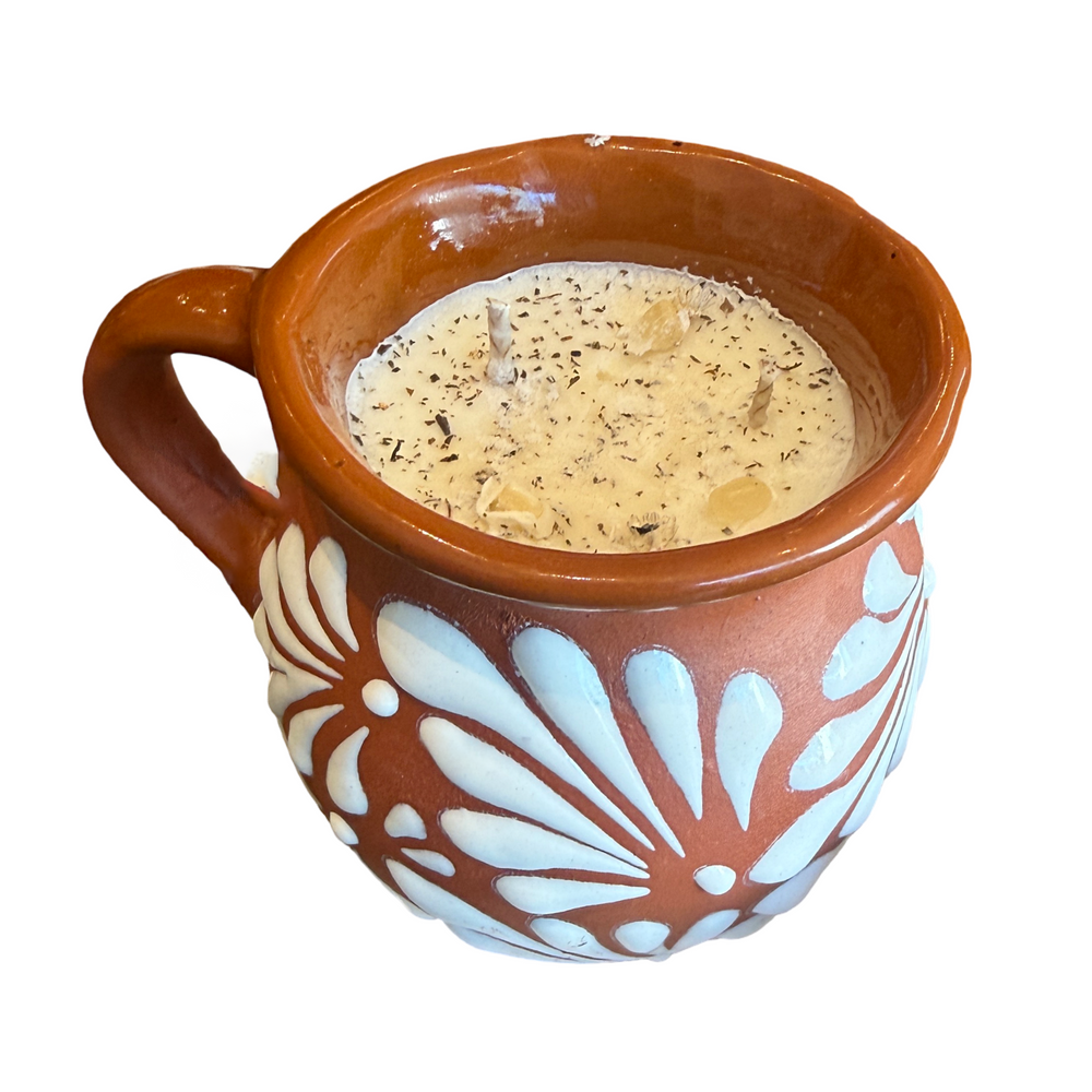 Terracotta mug with a white glazed talavera design filled with a multi wick ivory candle filled with dried botanicals.