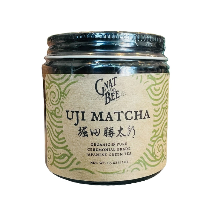 1.5 oz brown jar with match that features a brown label with a green design and black lettering.