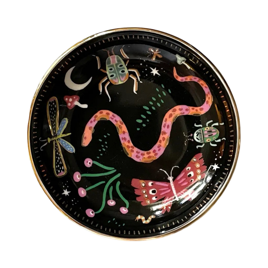 round black dish with a gold edge that features colorful insects and mushrooms.