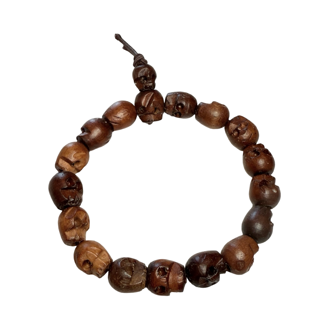 mala bracelet made of hand-carved wooden skull beads strung on a dark cord with tassel ends.