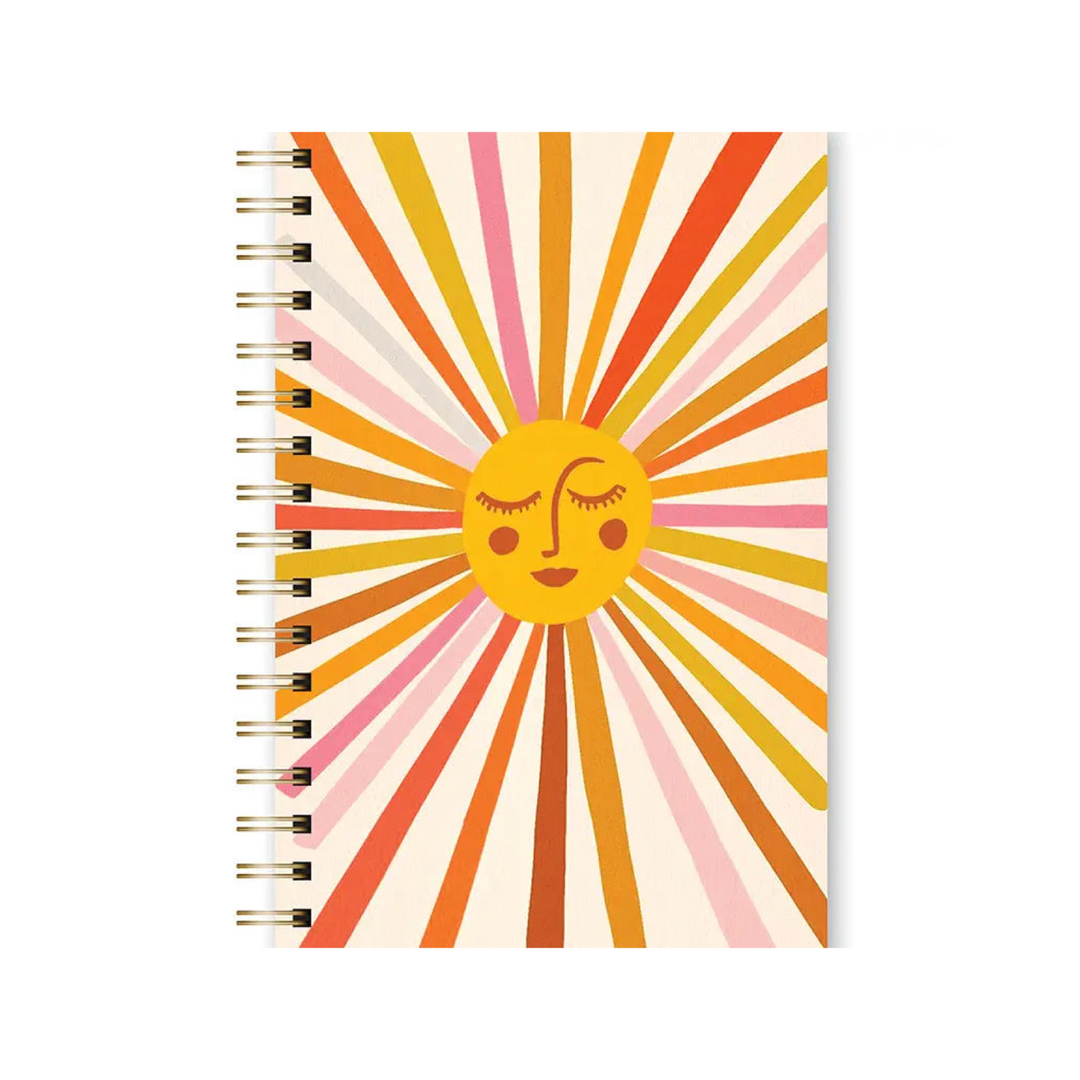 beige spiral notebook with an illustration of a sun with a smiley face featuring colors in orange, yellow, sienna and light pink.