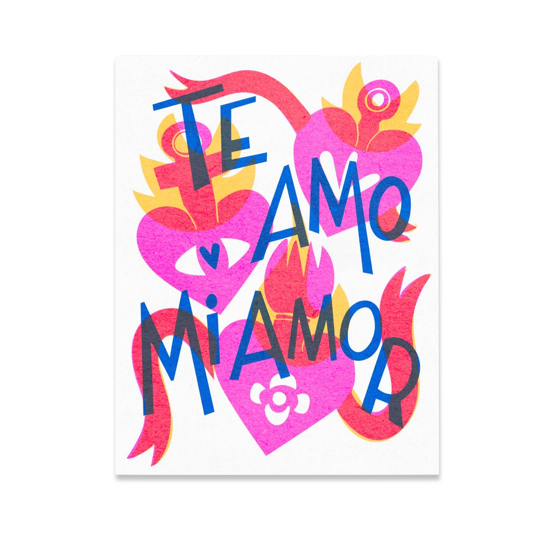white card featuring three ex-voto pink hearts, two red banners and the phrase Te Amo Mi Amor. (I love you my love)
