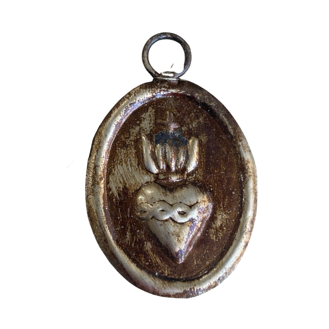 oval brass medallion with an image of the sacred heart in the center