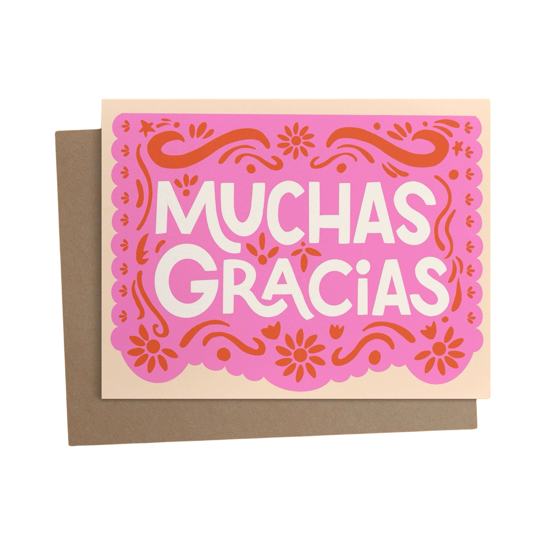 brown envelope behind a cream card with a pink and red papel picado design and the phrase muchas gracias in white lettering