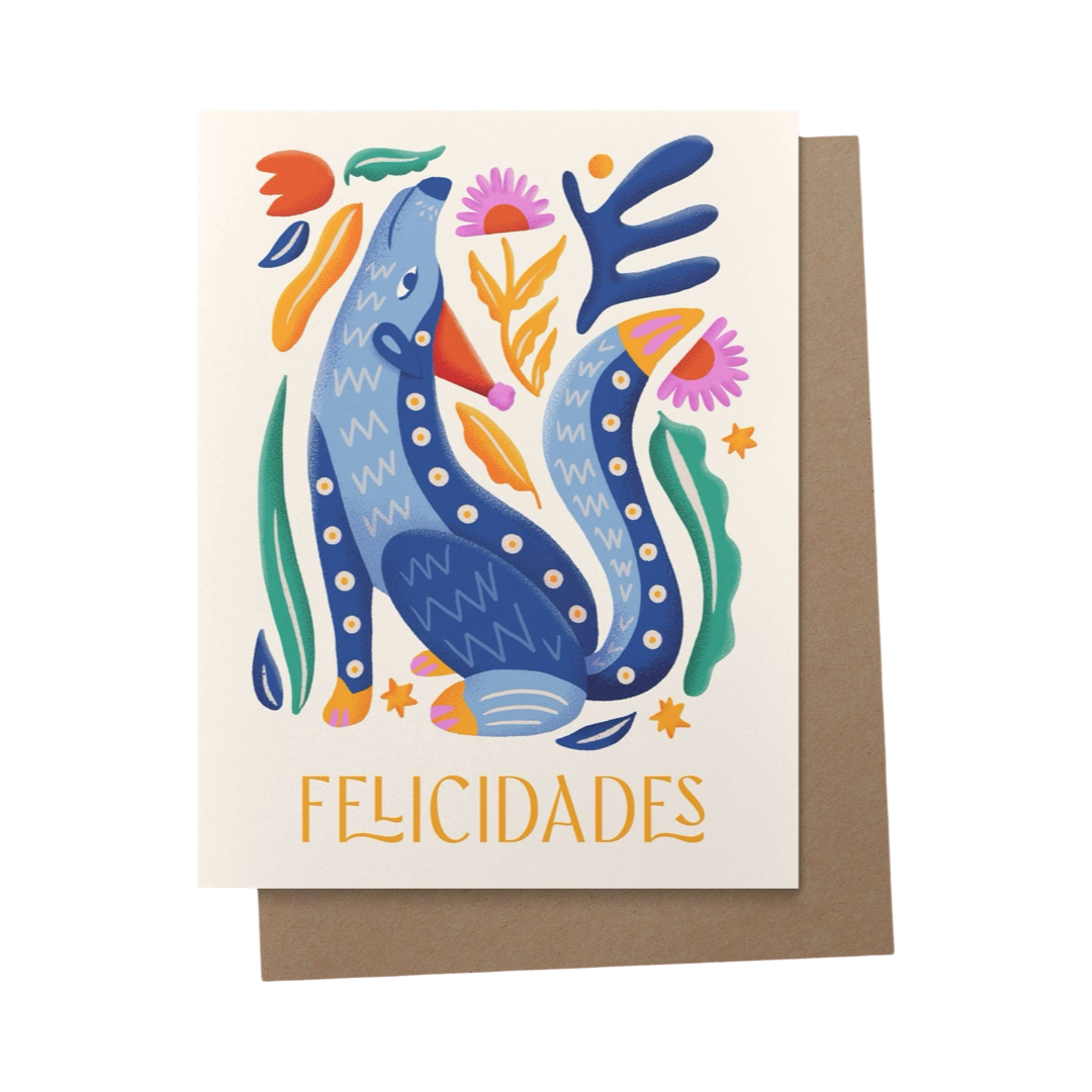 brown envelope behind a white card with a blue alebrije dog and the phrase Felicidades in yellow lettering