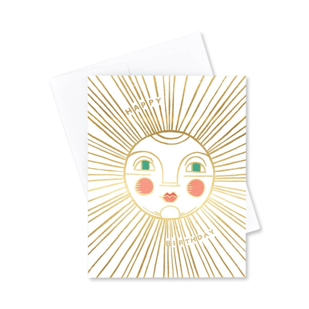 white card with an illustration of a sun in gold foil with a smiley face featuring teal eyes and the phrase Happy Birthday in gold lettering