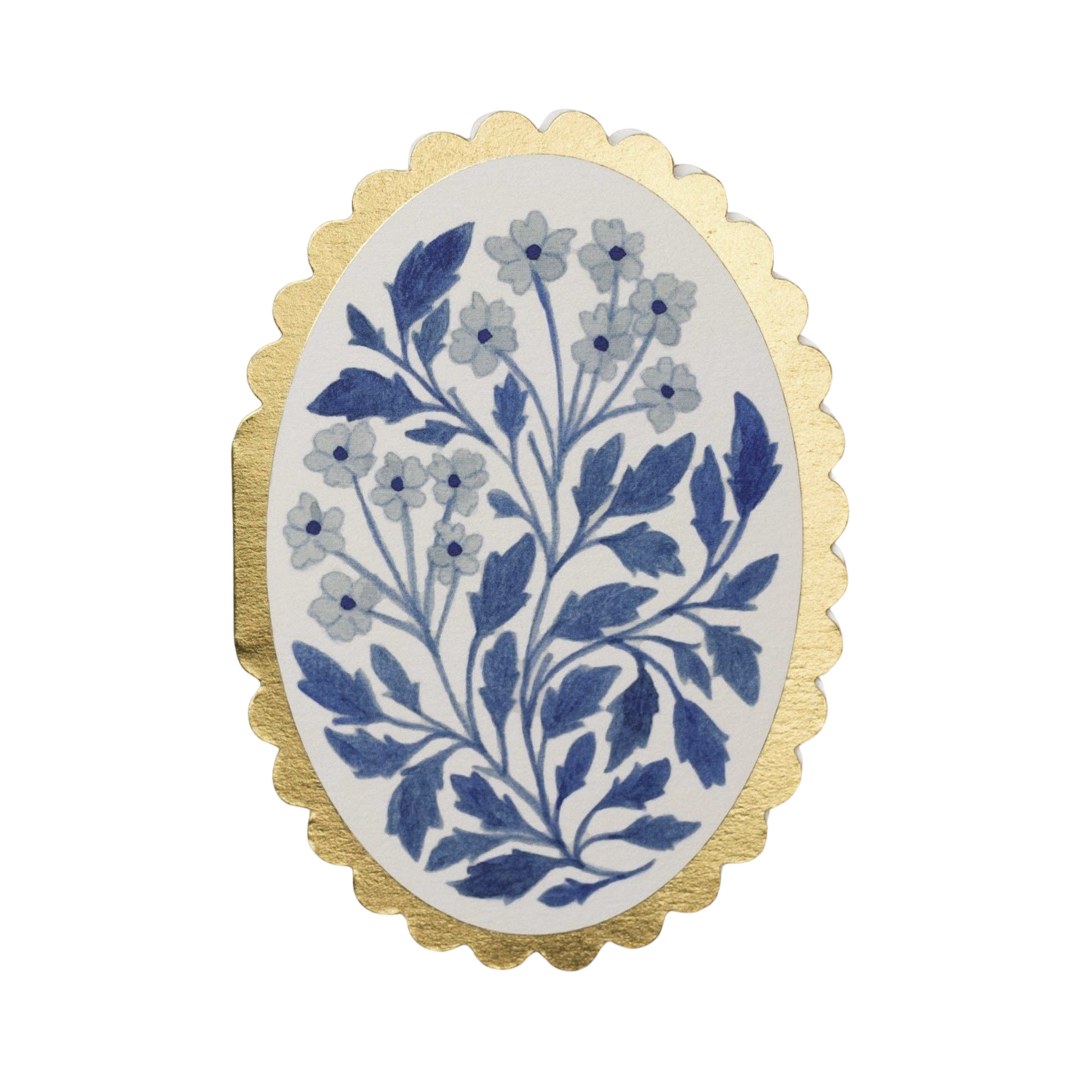 oval white card with a gold scalloped edge featuring a blue floral design in the center