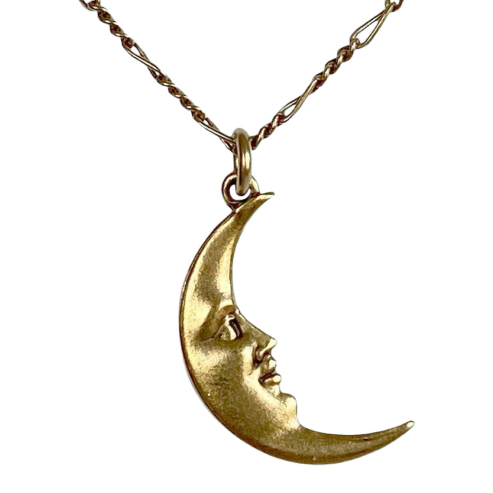 close up of a necklace with a gold crescent moon with a face charm
