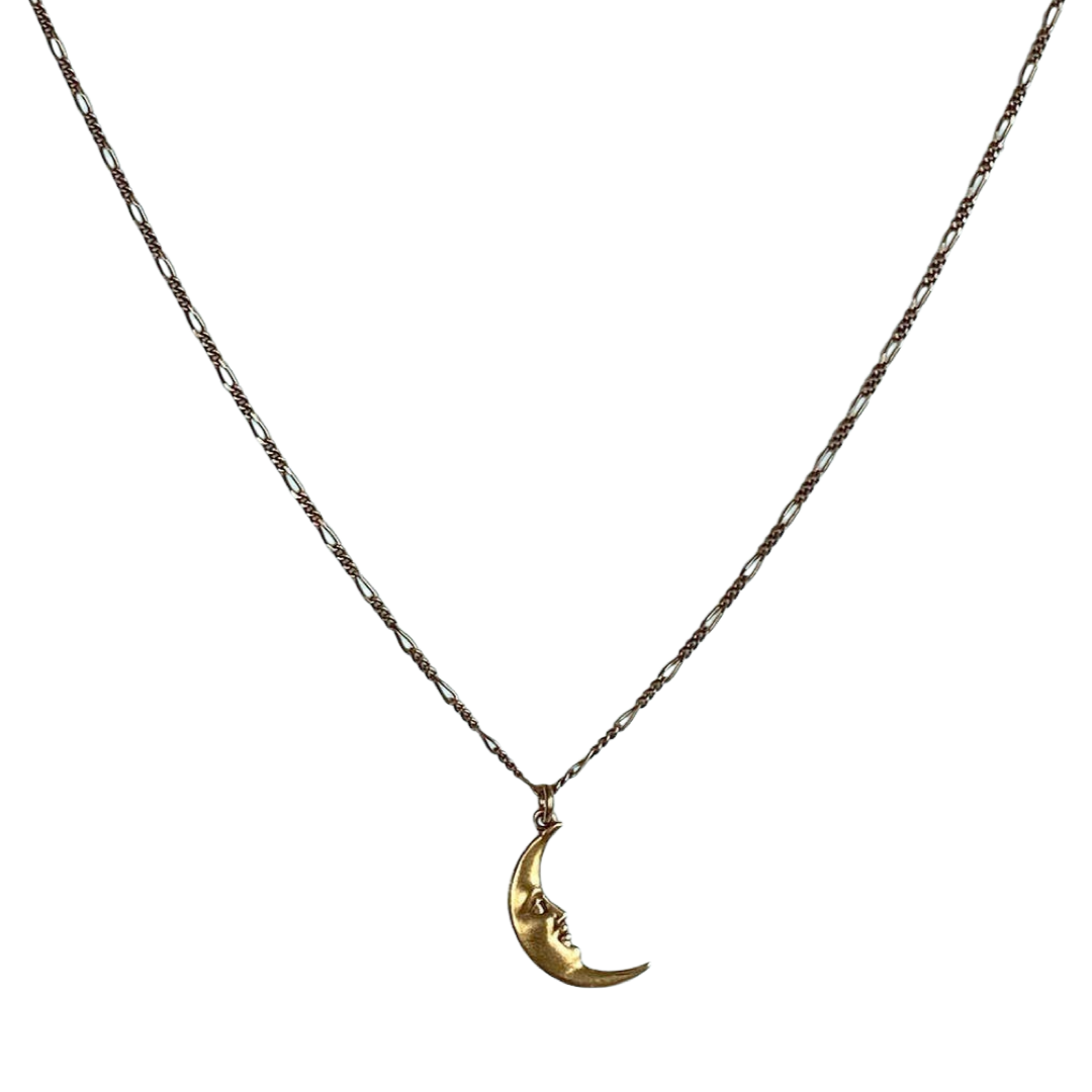 A necklace with a gold crescent moon with a face charm