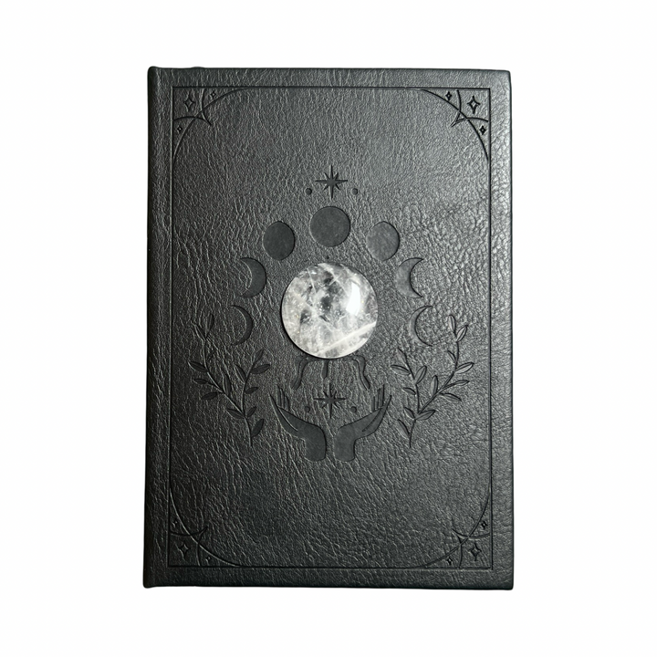 black vegan leather journal with the moon phases embossed on the cover with a round crystal quartz in the center.