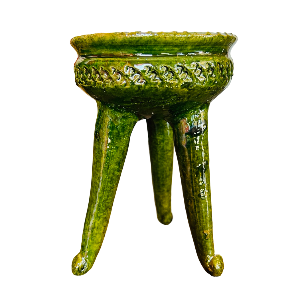 Side view of a three legged copalero, incense holder, with a green glaze.