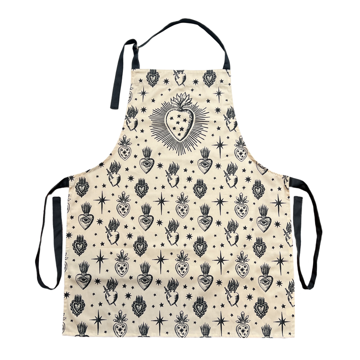 cream apron with images of various sacred hearts featuring heathered black neck and waist ties.