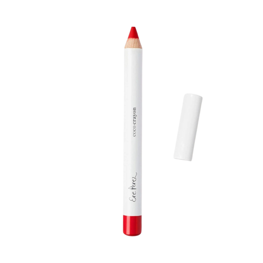 Red lip crayon in white packaging with black lettering and a white lid laying to the right of the crayon.