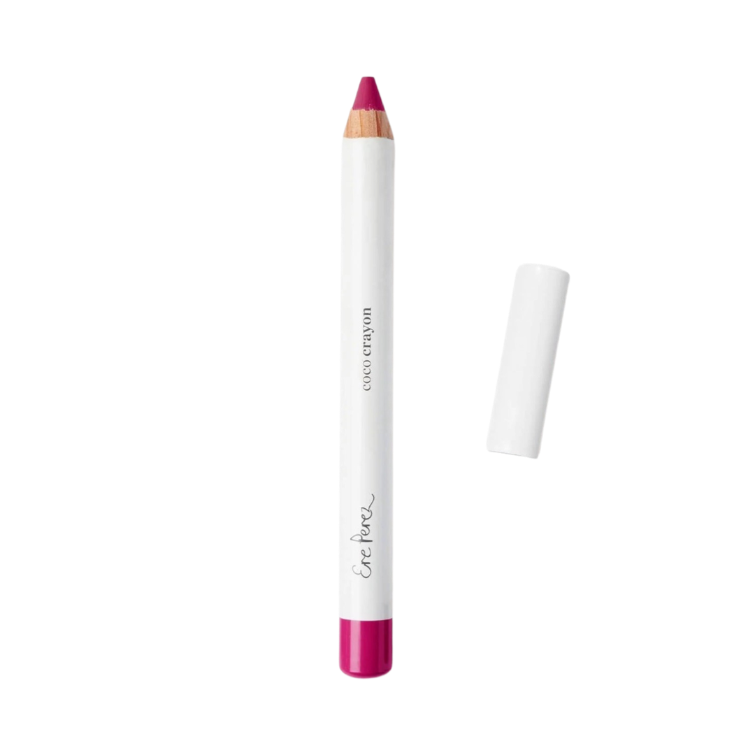 Fuschia lip crayon in white packaging with black lettering and a white lid laying to the right of the crayon.