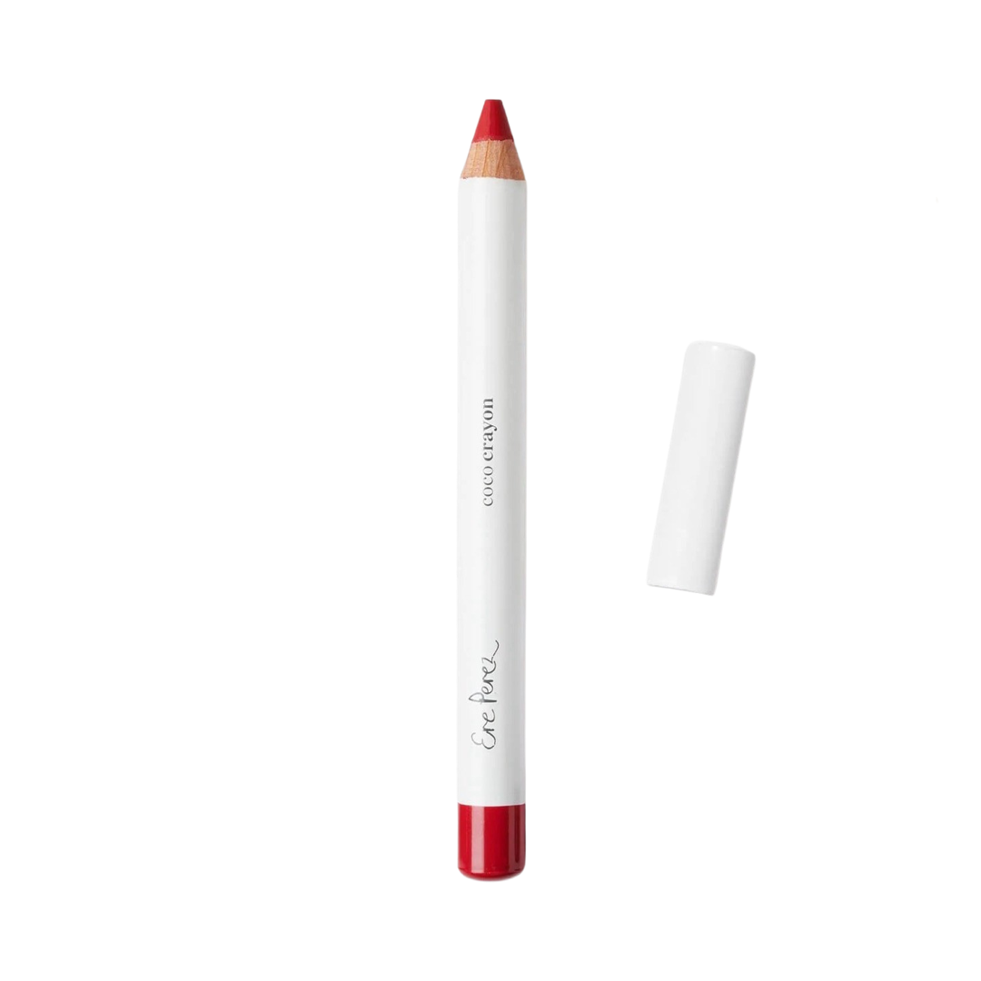 Red lip crayon in white packaging with black lettering and a white lid laying to the right of the crayon.