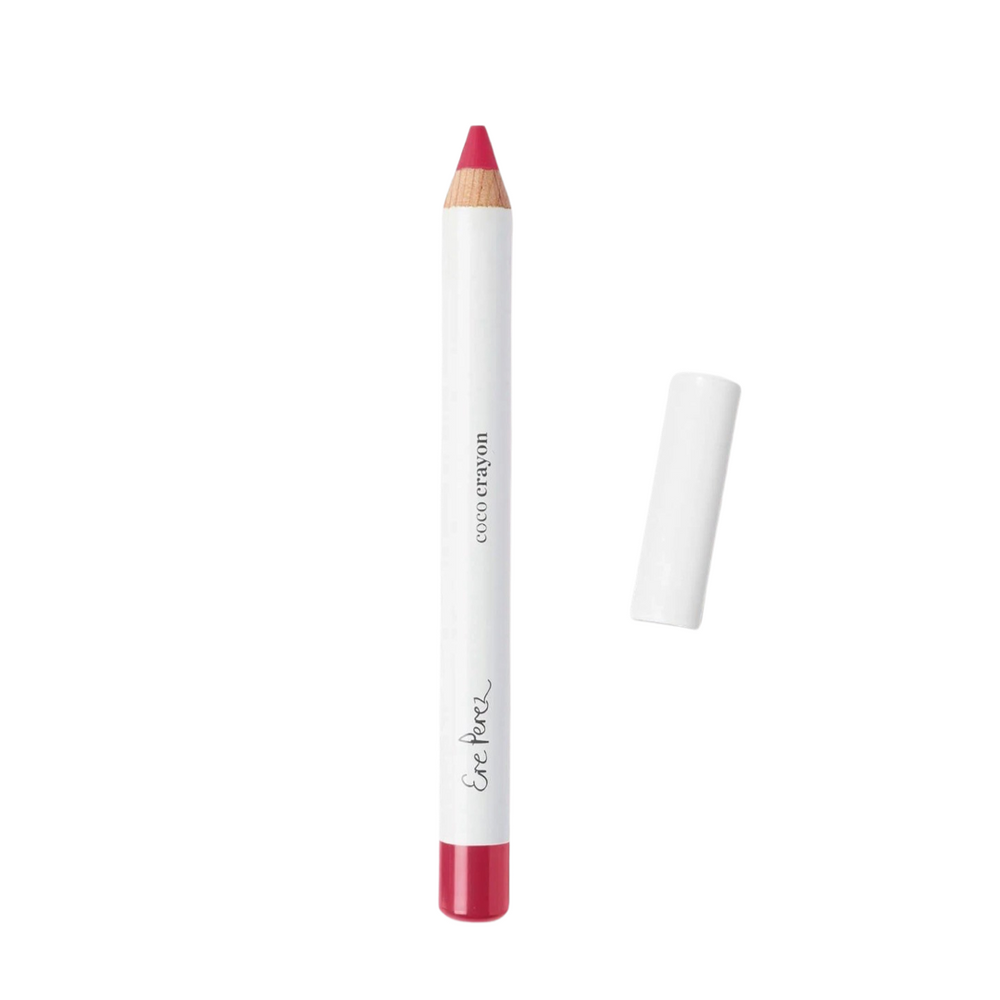 Pink lip crayon in white packaging with black lettering and a white lid laying to the right of the crayon.