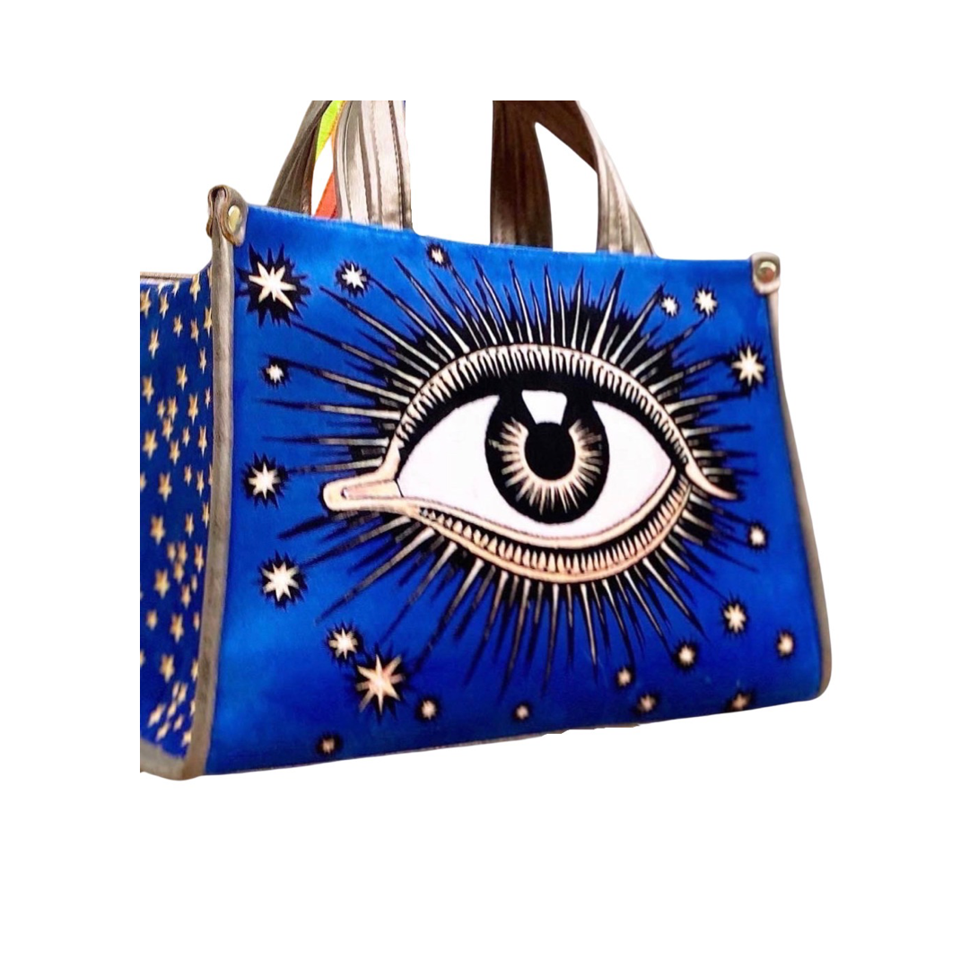 royal blue  hand bag with an image of an eye with sunbursts and sun rays. Brand: La Funky Mexicana