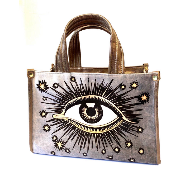 Silver hand bag with an image of an eye with sunbursts and sun rays. Brand: La Funky Mexicana