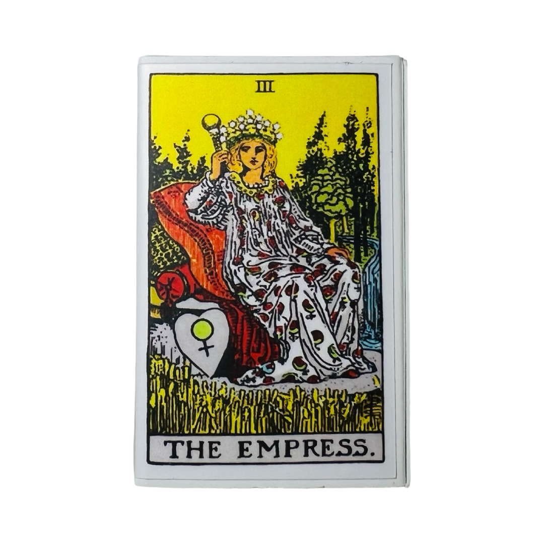 matchbox with an image of the Empress tarot card featuring a woman sitting on pillows with a crown.