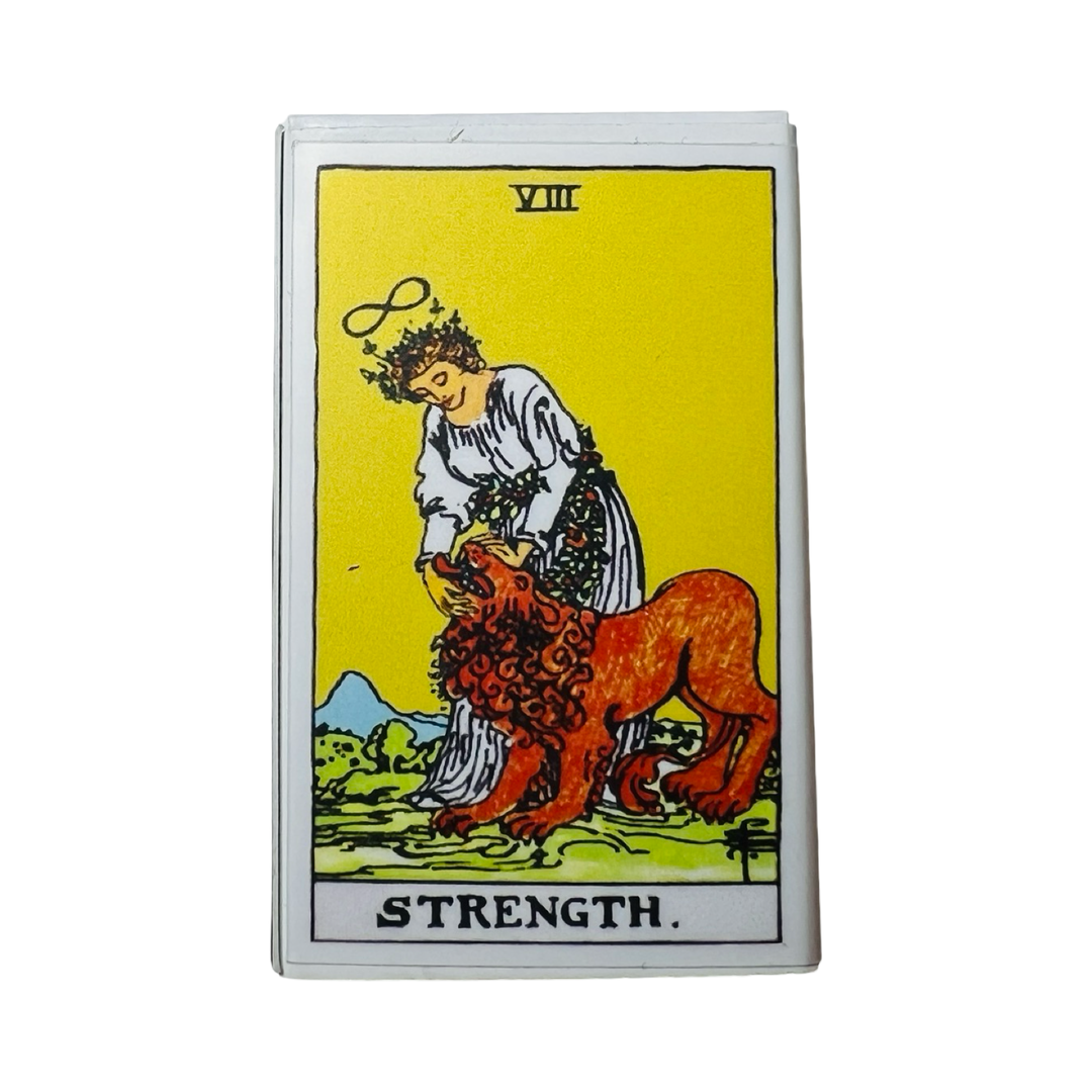 matchbox with an image of the Strength tarot card that features a woman and a lion.