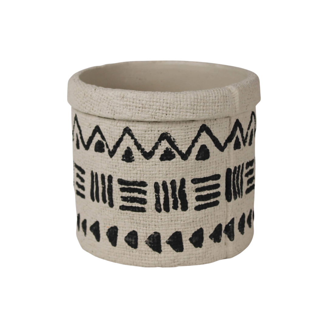 cement cylinder cachepot with black designs that feature triangles, lines and dots.