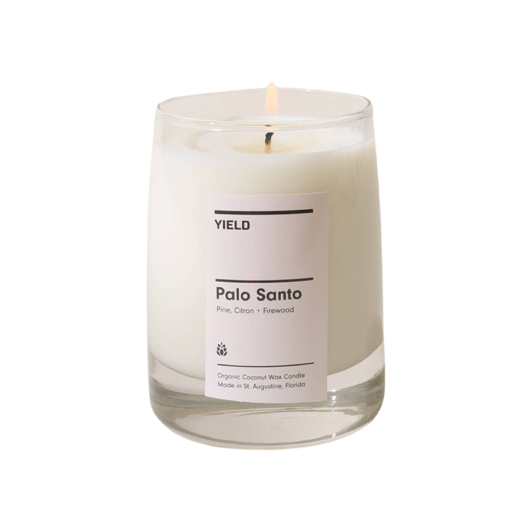 clear glass vessel with a white candle and features a white branded label with black lettering