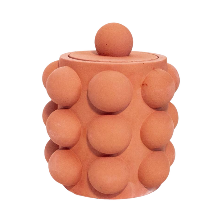 Terracota cylinder shaped candle vessel with a bubble texture and a lid.