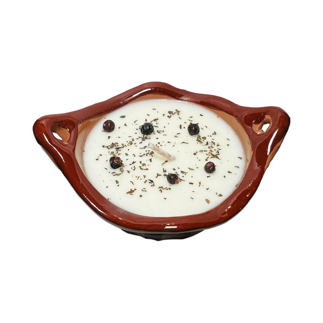 Top view of a candle that features dried flowers, crystals and dried herbs pressed into the white candle.