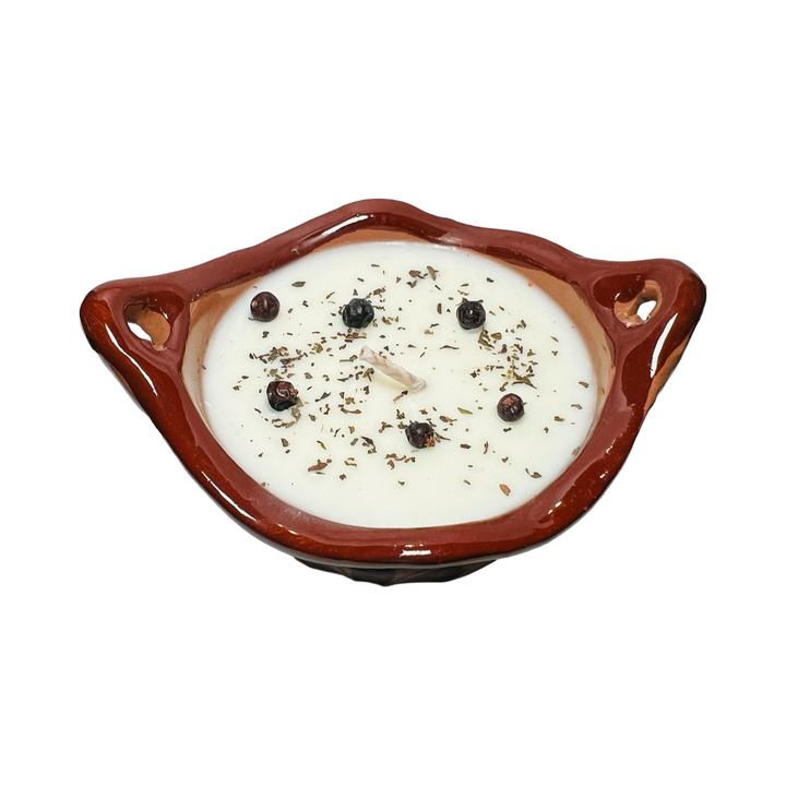 Top view of a candle that features dried flowers, crystals and dried herbs pressed into the white candle.