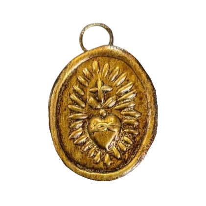 An oval-shaped bronze pendant featuring a raised design of a sacred heart surrounded by decorative floral patterns, with a small loop at the top for hanging or wearing.