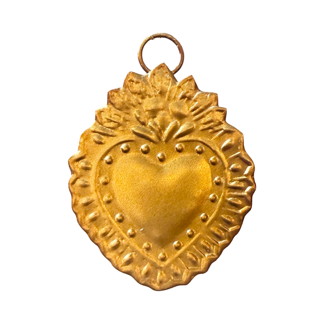 Gold heart-shaped pendant with intricate designs on a white background
