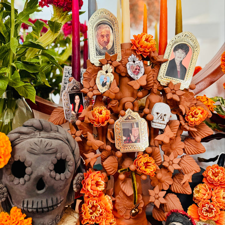 Decorative altar with skulls, photos, and flowers on a table.