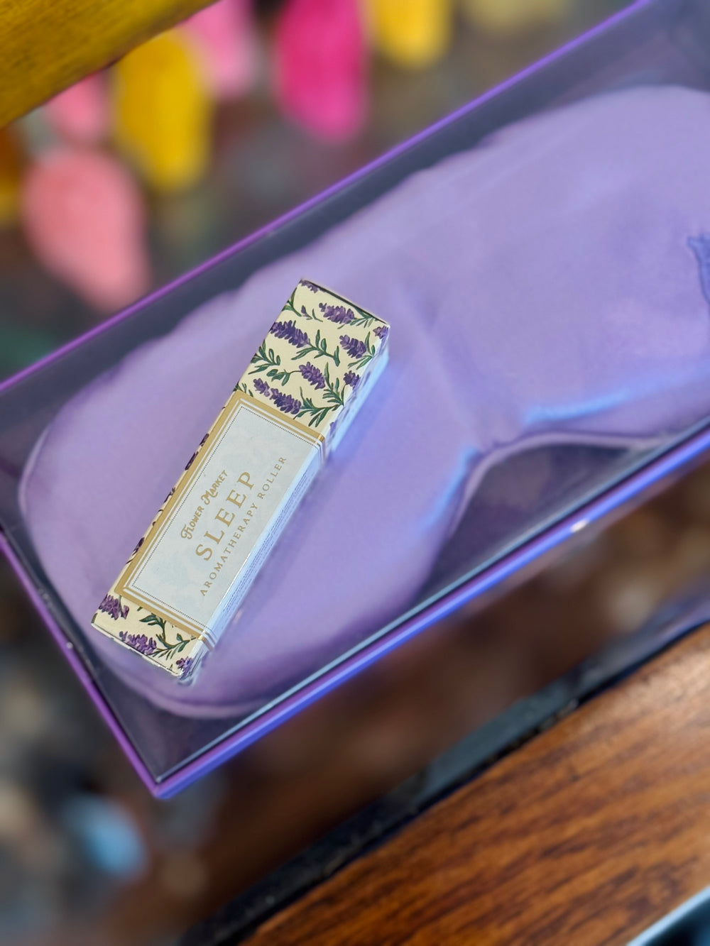 Purple eye mask with a small box featuring floral design on a wooden surface.