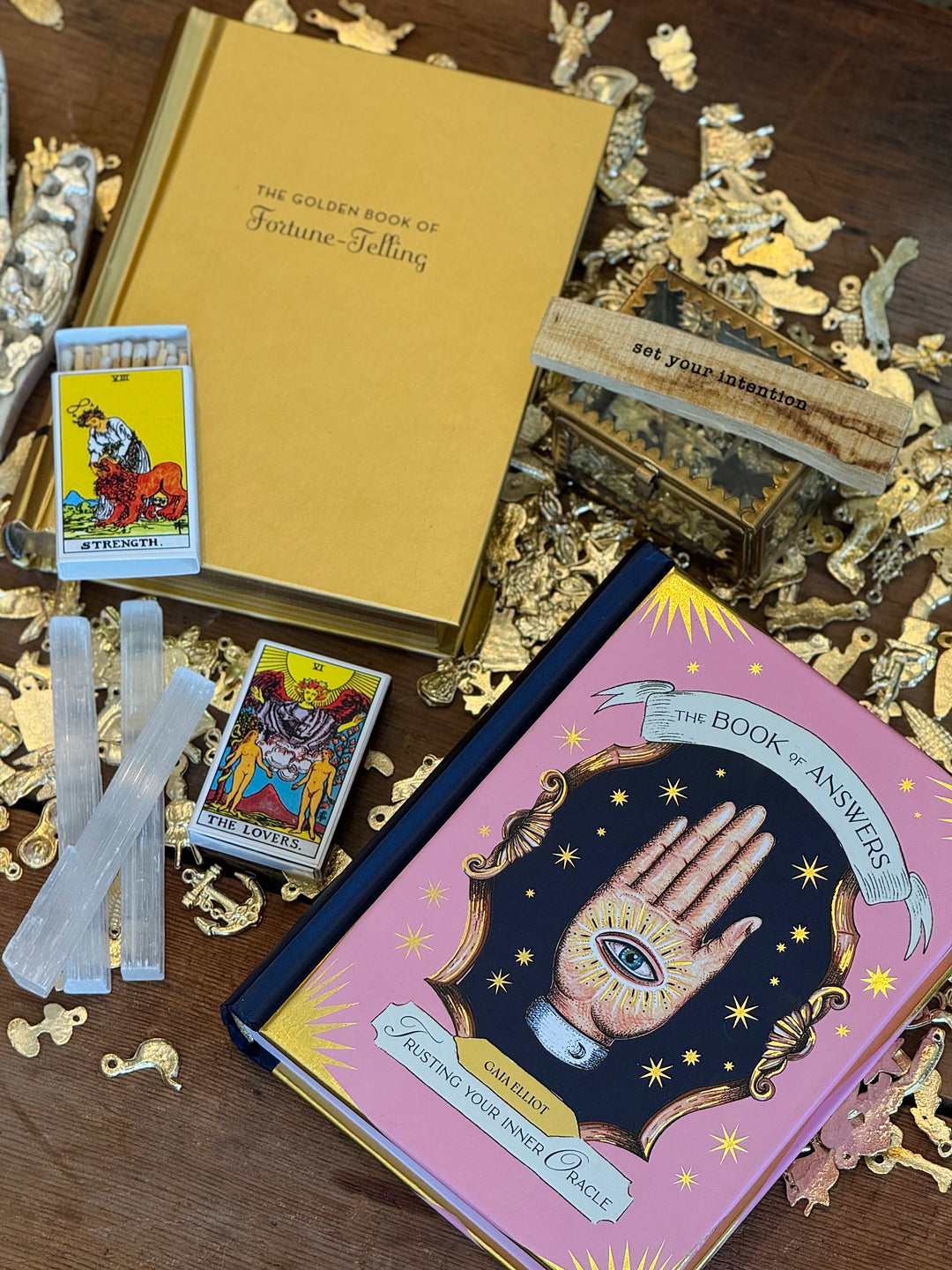 Close up room view displays fortune telling themed books, tarot cards and accessories on a wooden surface.
