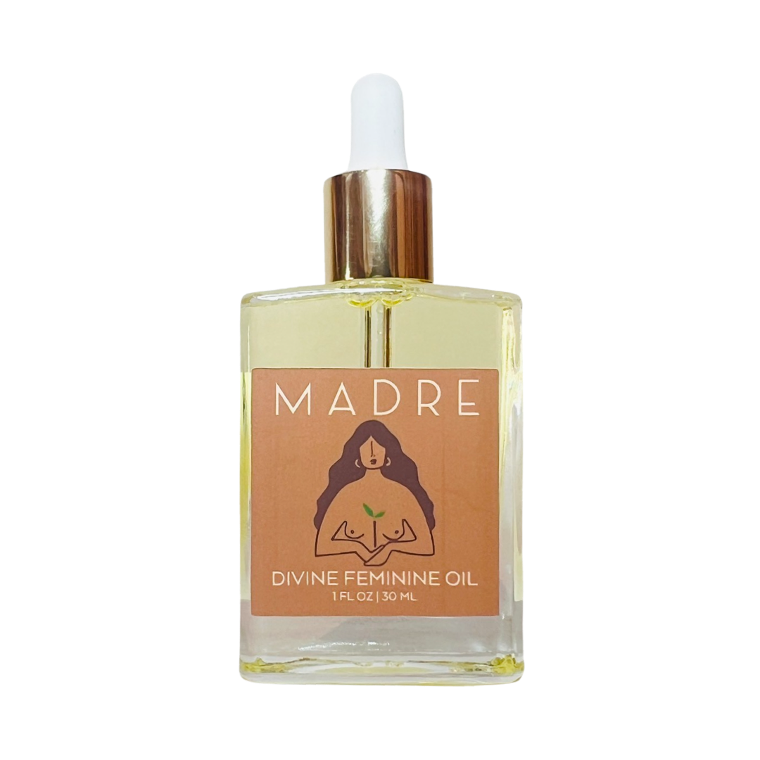 clear 1 oz glass bottle of divine feminie oil with a sienna branded label that features a topless long haried woman holding a plant.. Brand: Salud