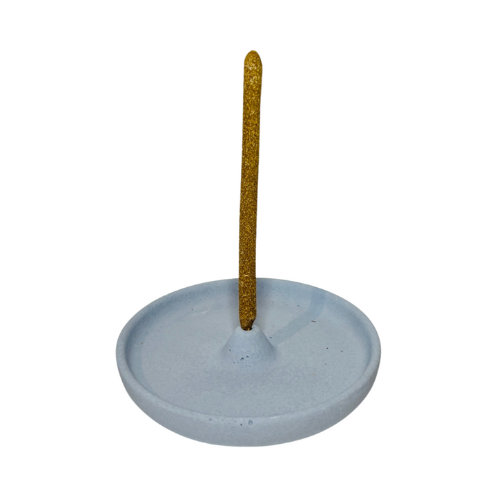 round dusty blue incense holder with an incense stick in it