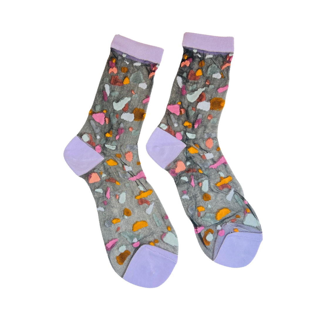 pair of sheer socks with a dark gray background with multi-color fragments and matching lavender accents on toes and heels