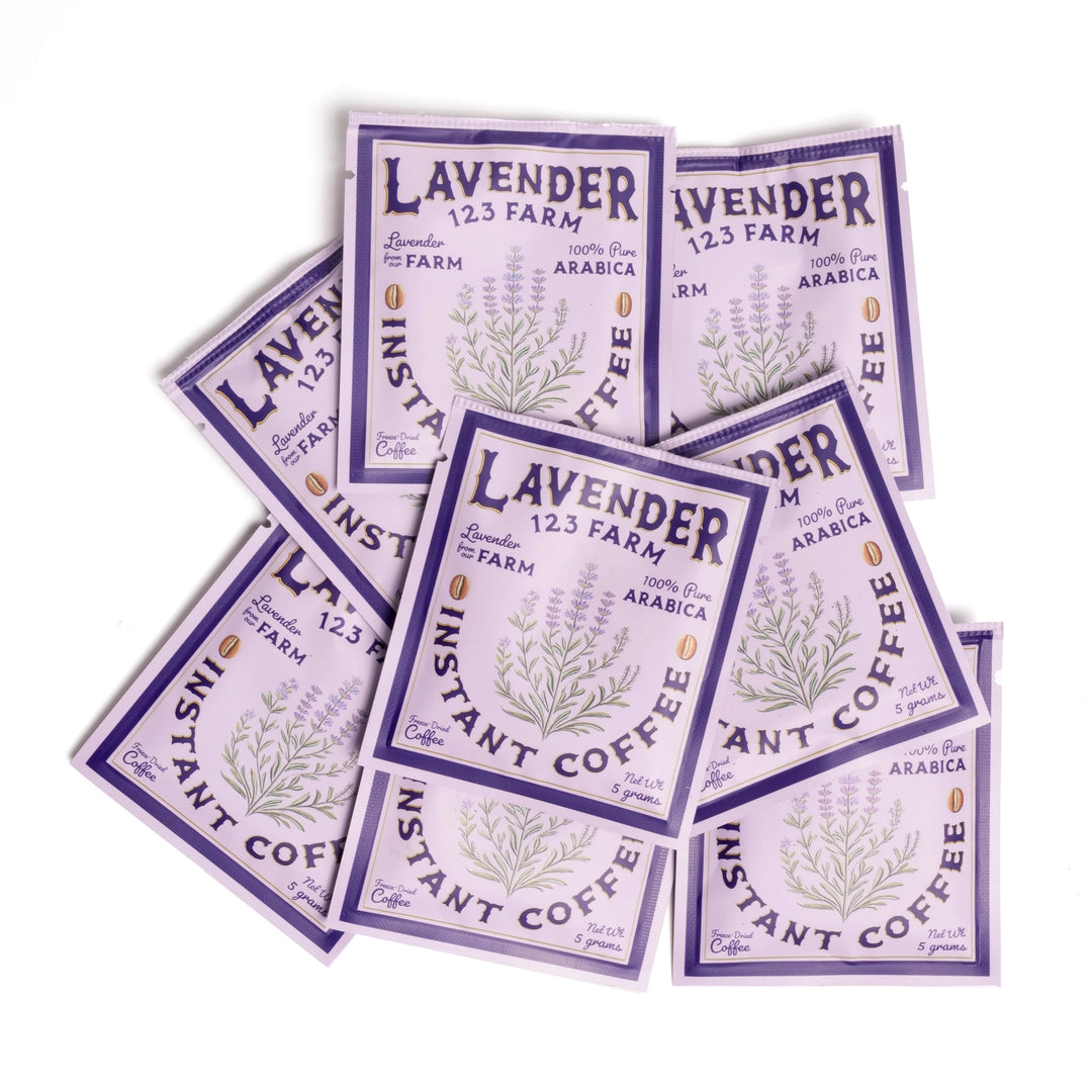 8 Purple packets of Lavender 123 Farm instant coffee scattered together.