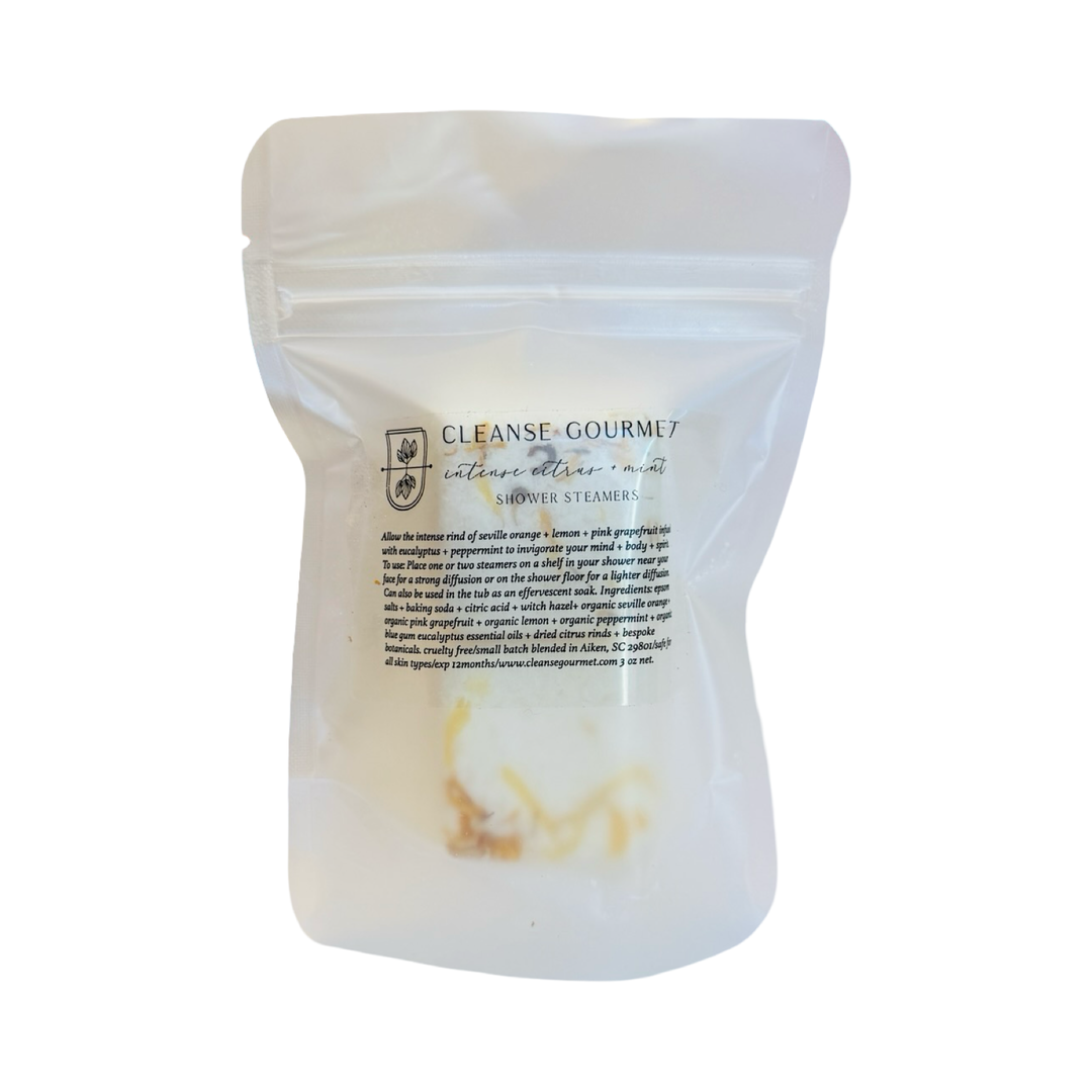 Citrus shower steamers with dried botanicals shown alongside a resealable Cleanse Gourmet pouch.