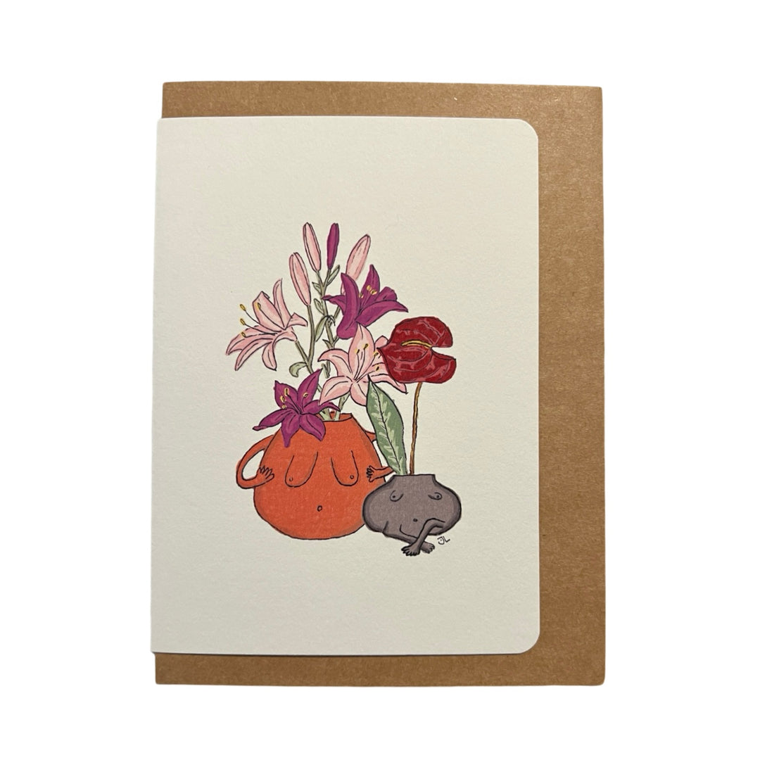 Illustration of a terracotta planter with a torso-like design, filled with pink and purple flowers, alongside a smaller black planter with a similar torso shape, on a greeting card paired with a kraft envelope.