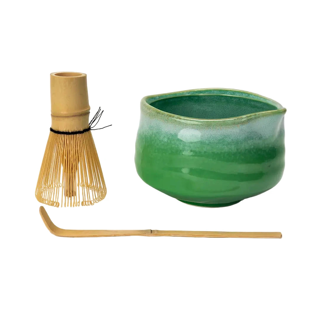 Side view of a green matcha bowl, whisk and bamboo spoon.