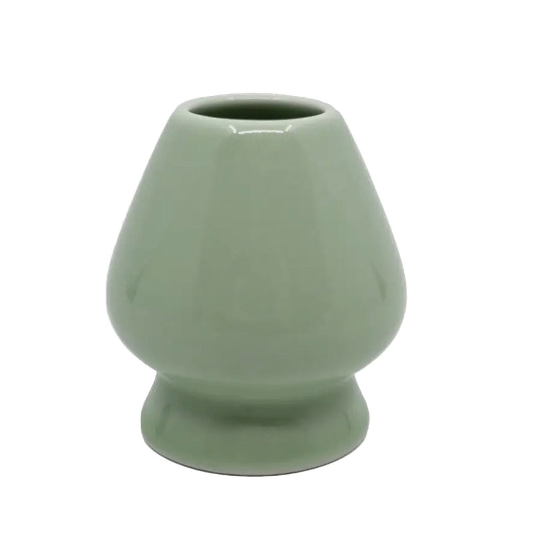 Light green ceramic whisk stand in front of a white background.