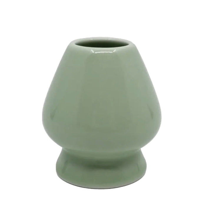 Light green ceramic whisk stand in front of a white background.