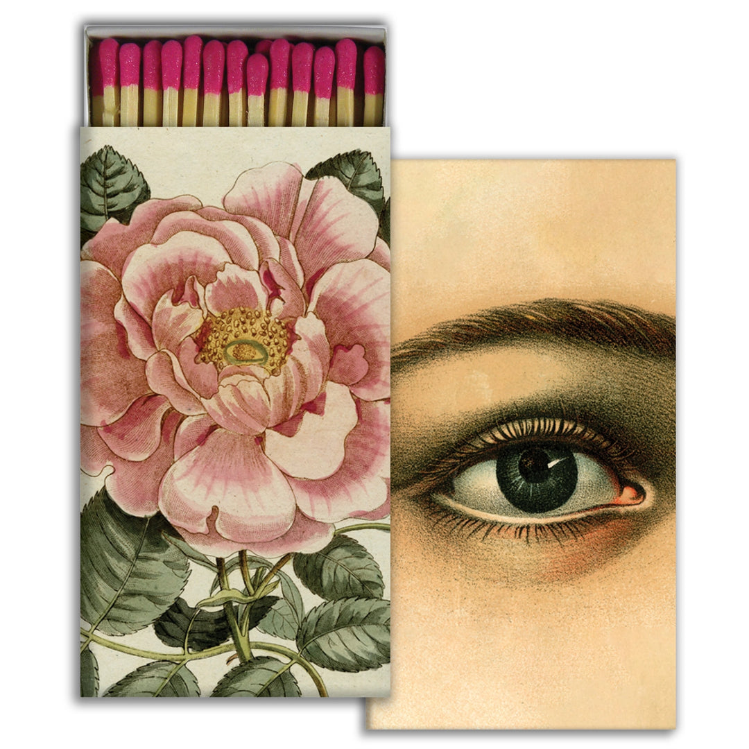 matchbox with pink-tipped matches featuring an illustration of a large pink rose on the cover, and backside with a detailed illustration of a single eye.